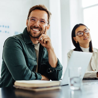 Business man listening to a discussion during a meeting in an office. Happy business man sitting in a boardroom with his colleagues.