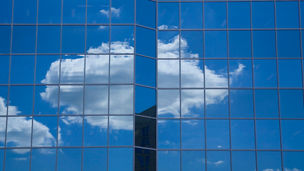 A single cloud seen reflected on office building