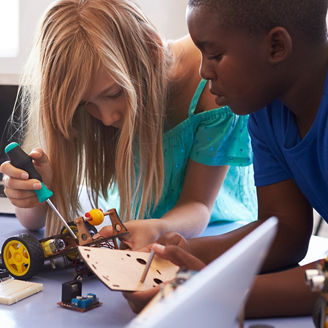 There are two children busy tinkering with a tractor