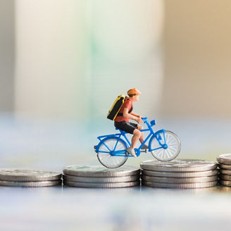 Photo showing a male figure cycling up a mountain of coins