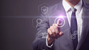 A man, wearing a suit, points to a virtual screen displaying floating icons representing various industries