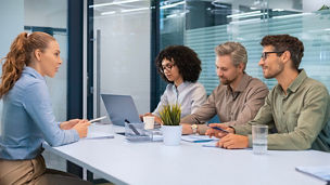 A group of people are sitting at a table in a meeting room
