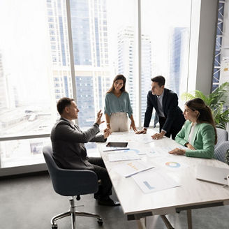 People are sitting around a table in a modern office setting and are having a conversation
