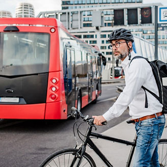 A man riding a bike on a bridge as a bus passes by