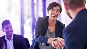 Twee mensen die elkaar de hand schudden in een vergaderruimte.