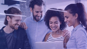 Grupo de colegas a sorrir enquanto observa um portátil num ambiente de escritório moderno.