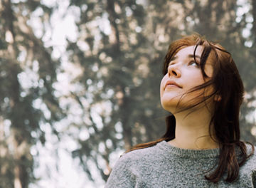 woman looking up in forest