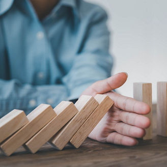Close-up of a businessman's hands stopping a domino effect