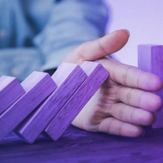 Close-up of a businessman's hands stopping a domino effect