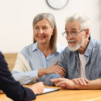 Two older adults sit with a staff member during an appointment