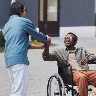 man holding hand with a person in a wheelchair