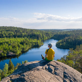 Man sitting on cliff looking at landscape