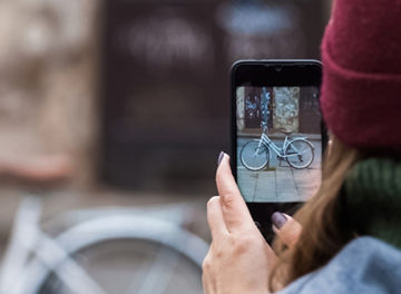 woman takes picture of bicycle with mobile phone