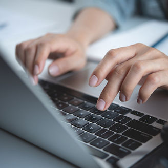 Hands are typing on the keyboard of a computer