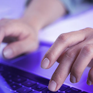 Hands are typing on the keyboard of a computer