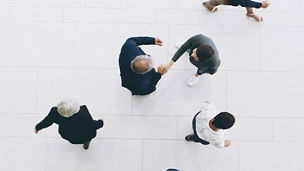 A top view on people, and two of them are shaking hands.