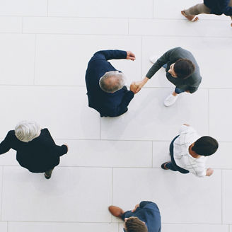 A top view on people, and two of them are shaking hands.