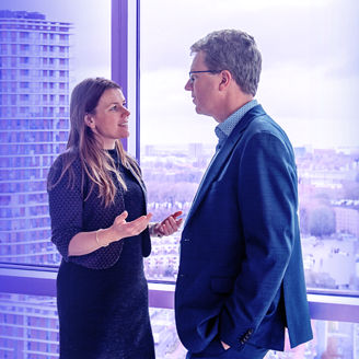 Two colleagues talking in front of a window