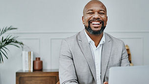 A bald man laughing wearing grey coat