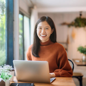 A girl smiling while working on laptop