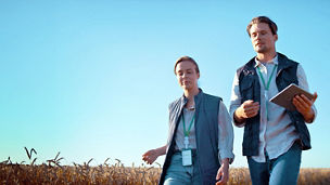 A man holding a tablet walking with women in a field