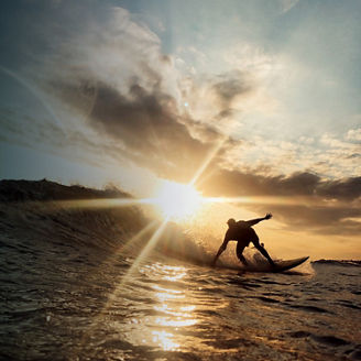 Een man is op golven aan het surfen tijdens zonsondergang