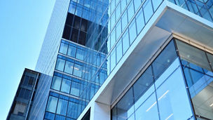 Bottom view of modern skyscrapers in business district against blue sky. Looking up at business buildings in downtown.