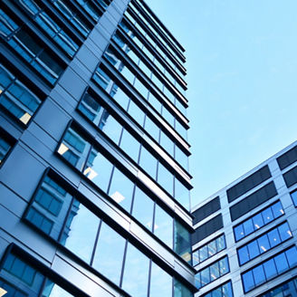 Bottom view of modern skyscrapers in business district against blue sky. Looking up at business buildings in downtown.