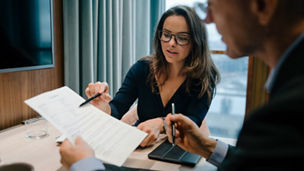 Male and female entrepreneur brainstorming over document during meeting in office