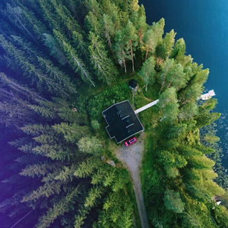 Aerial view of a cottage in the forest next to a lake