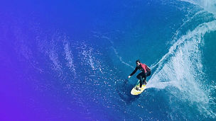 Aerial view of surfer riding a turquoise wave banner