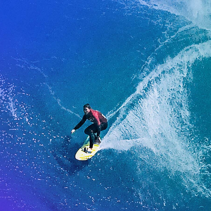 Aerial view of surfer riding a turquoise wave banner