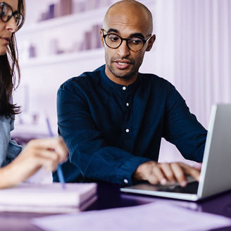 Business man using a laptop and discussing with his colleague in an office. Black business man having a meeting with a female professional.; Shutterstock ID 2363383347; purchase_order: advisory assurance; job: anne; client: ai