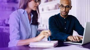 Two people behind laptop