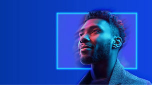 Man looking up with his face illuminated in front of a rectangular neon portal