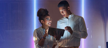 Two colleagues in front of a glowing light box with cobalt gradient