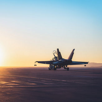 Aircraft on airstrip against setting sun