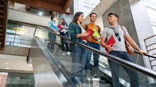 Students on escalator after class at college talking and smiling