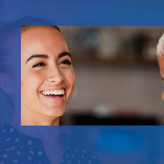 Two women colleagues laughing while standing in a cafe at their workplace. One of the women is holding a take out hot drink cup.