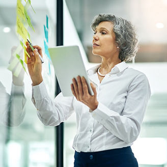 Cropped shot of a mature businesswoman writing notes on a glass wall in a modern office
