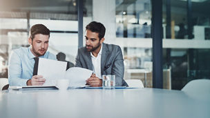 Shot of two young businessmen going through paperwork together in a modern office