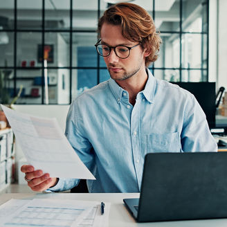 Review, document and man in office with laptop, glasses or preparation of financial statement. Reading, audit paper or analyst in workplace with tech, data entry or balance sheet in budget management