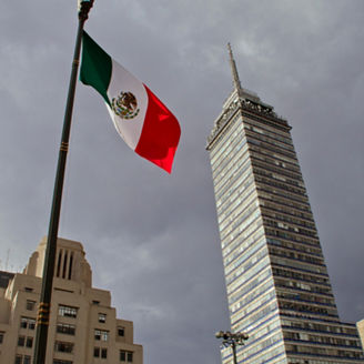 Fotografía de la bandera mexicana frente a la torre Latino