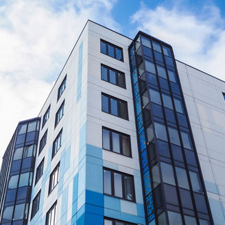 An affordable housing apartment block against a blue and cloudy sky