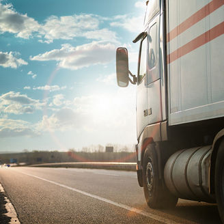 Arriving white truck on the road in a rural landscape at sunset