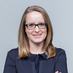 Porträt von Astrid Kristof vor einer hellgrauen Wand