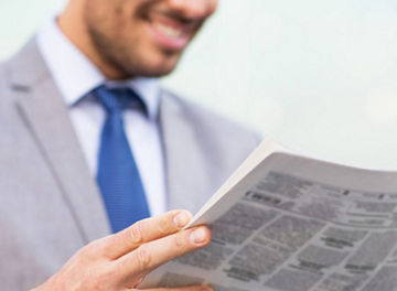 新聞を読む青いネクタイのビジネスパーソン