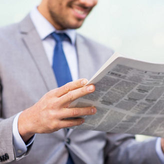 新聞を読む青いネクタイのビジネスパーソン