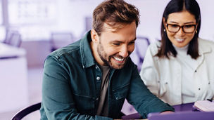 Successful business man using a laptop in a meeting with his colleague. Happy business man playing a slideshow presentation in an office.; Shutterstock ID 2304643873; purchase_order: marketing advisory assurance; job: Anne; client: AI campagne