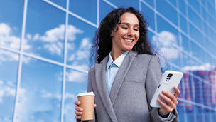Woman smiling while holding phone and coffee